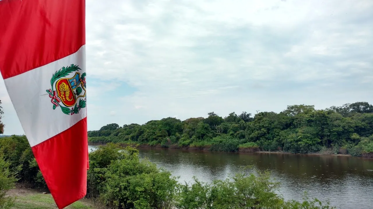 Peruvian flag beside a river and forest